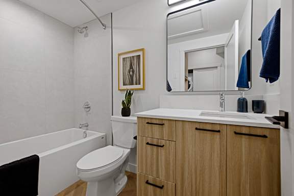 A bathroom with a toilet, sink, and mirror.