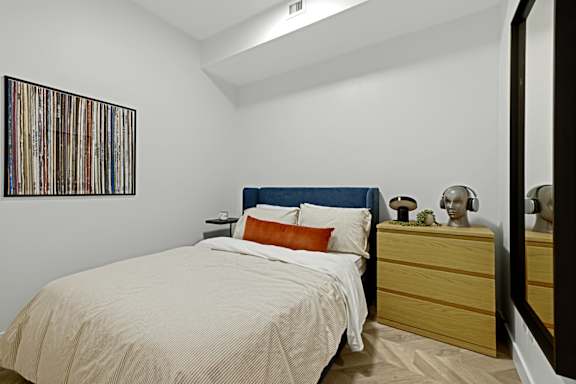 A bedroom with a bed, nightstand, and a picture on the wall.