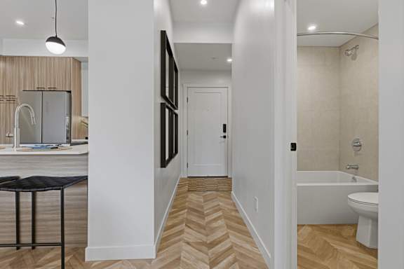 A bathroom with a white tub and a wooden floor.