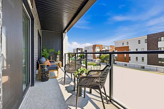 A balcony with a table and chairs overlooking a building.