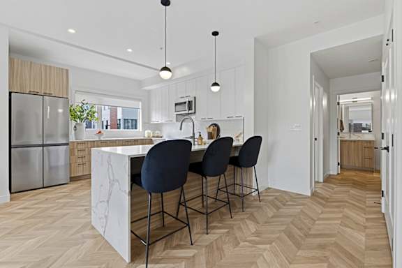 A kitchen with a marble island and four chairs.