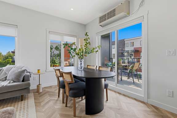 A dining room with a table and chairs and a couch.