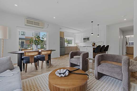 A living room with a grey couch, a wooden coffee table, and a large window.