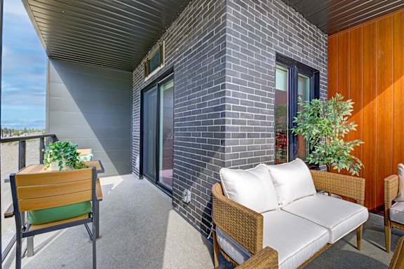 A patio with a couch, chair and plants.
