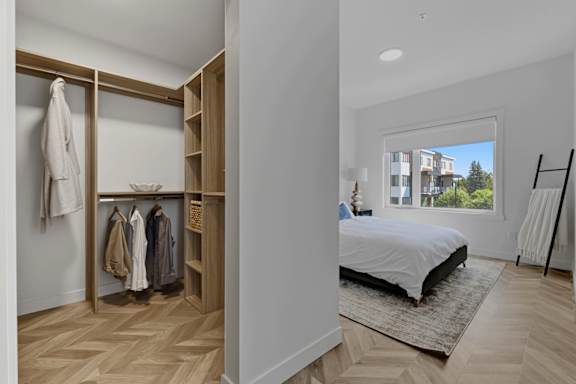 A bedroom with a large bed and a wardrobe with clothes hanging on it.