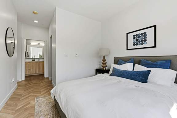 A bedroom with a large bed and a mirror on the wall.