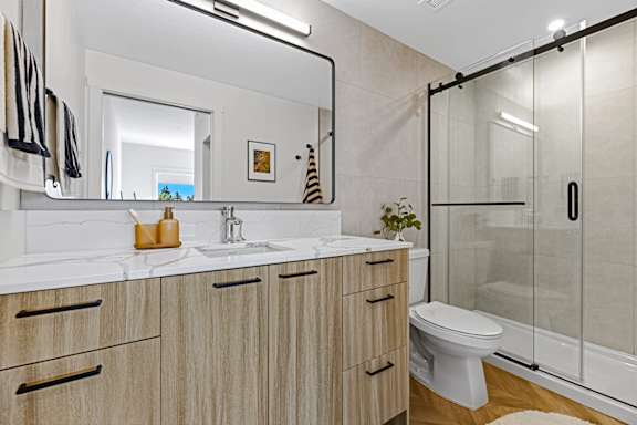 A bathroom with a white toilet, sink, and wooden cabinets.