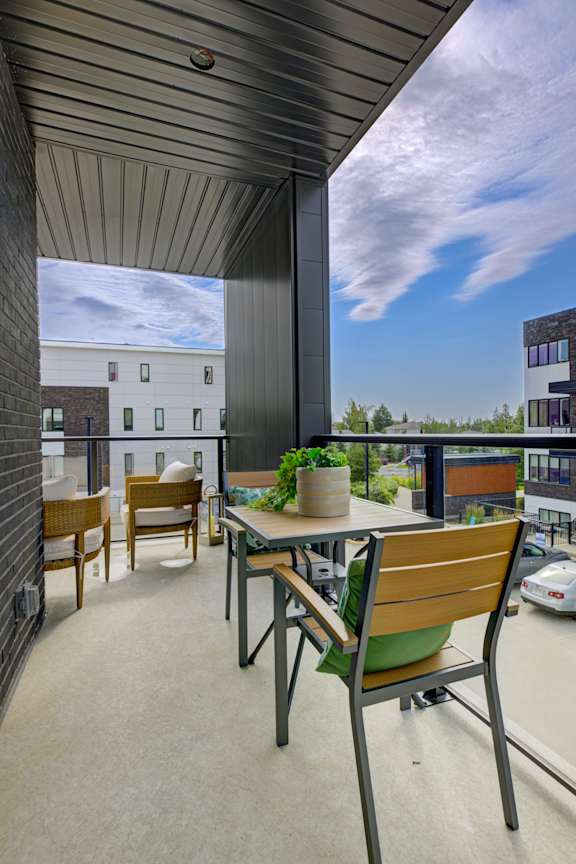 A patio with a table and chairs overlooking a parking lot.