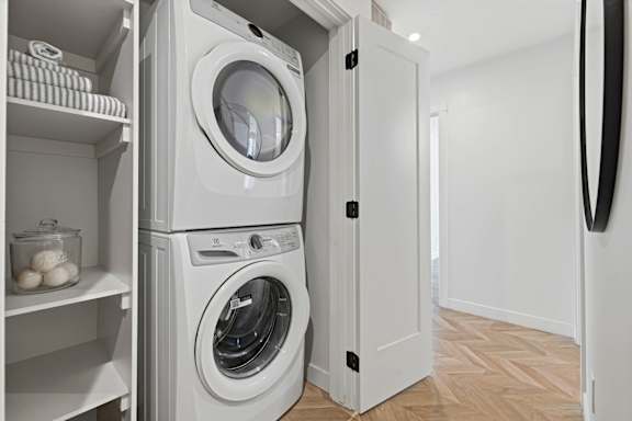 A white laundry room with a washer and dryer stacked on top of each other.