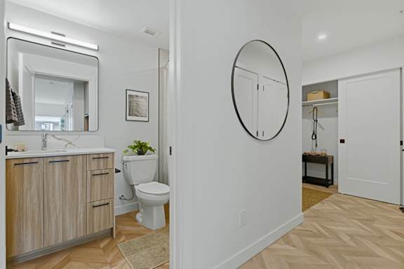 A bathroom with a toilet, sink, and mirror.