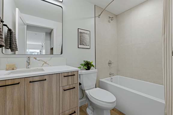 A white toilet sits next to a white bathtub in a bathroom.