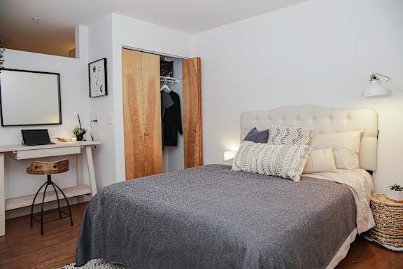 A bedroom with a bed, desk, and chair.