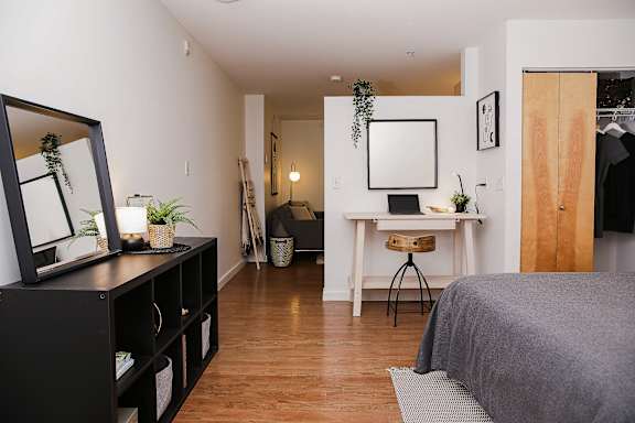 A bedroom with a bed, desk, and mirror.