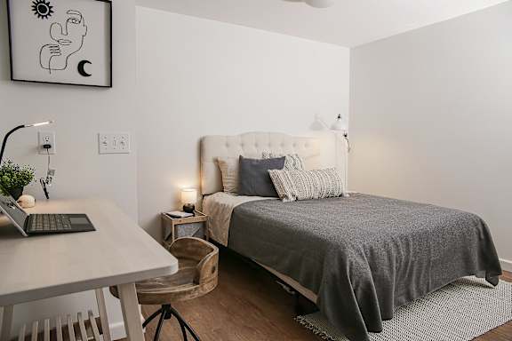 A bedroom with a bed, a desk, and a chair.