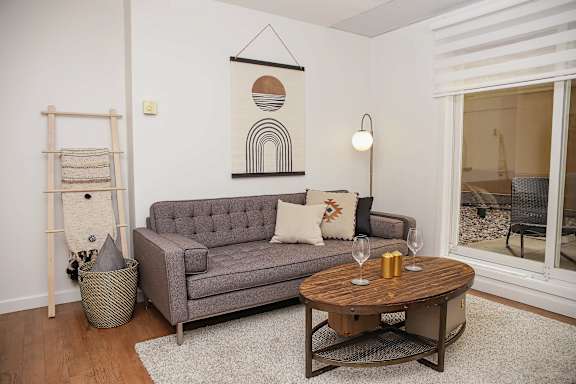 A grey couch with a wooden coffee table in front of it.