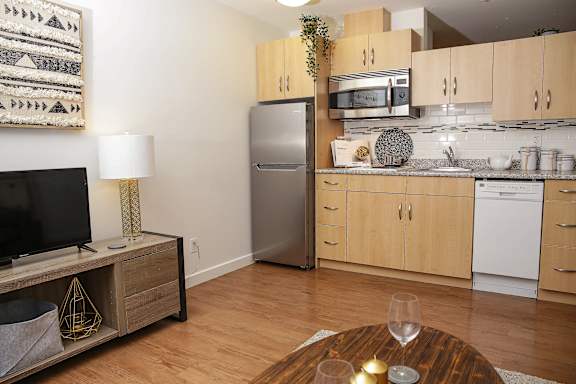 A modern kitchen with wooden floors and a white fridge.