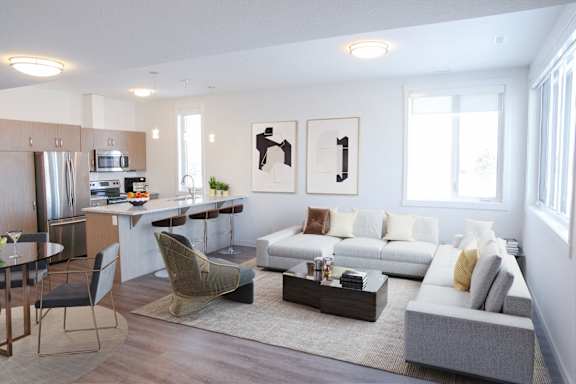A modern living room with a grey sofa, a coffee table, and a dining table with chairs.