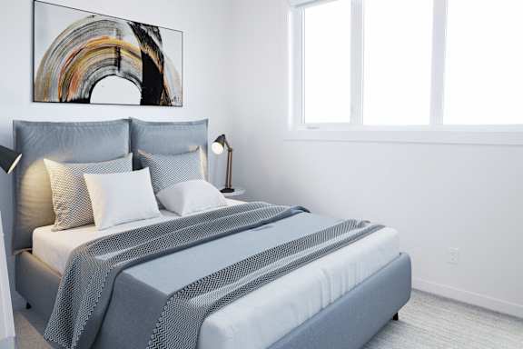 A bed with a grey comforter and pillows is in a room with a large painting on the wall.