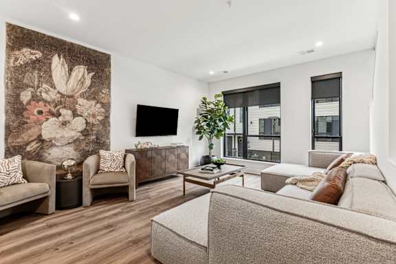 A living room with a large tapestry on the wall and a couch with a pillow on it.