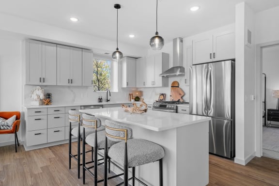 a white kitchen with a large island with three stools