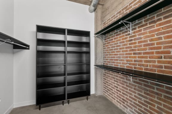 a room with a brick wall and two black shelves