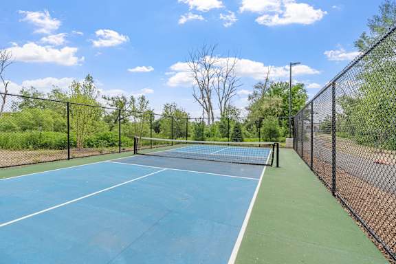 A tennis court surrounded by a fence and trees.