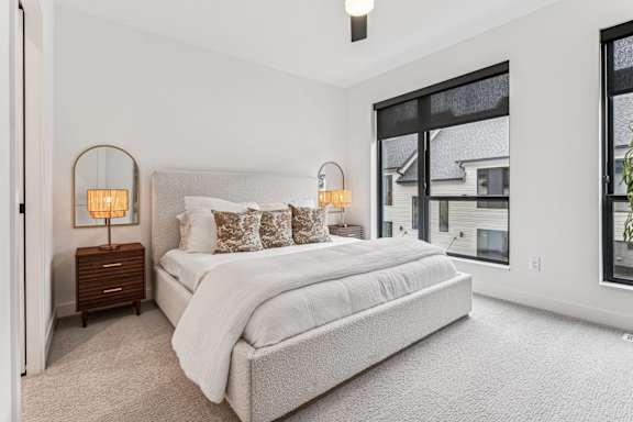 A bedroom with a large bed and two lamps on side tables.