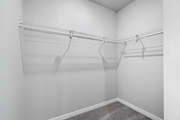 the closet of a studio apartment with white walls and hanging racks