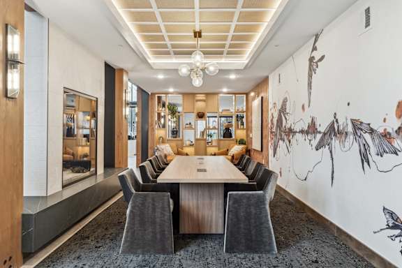 A conference room with a long table surrounded by chairs and a wall mural of birds.
