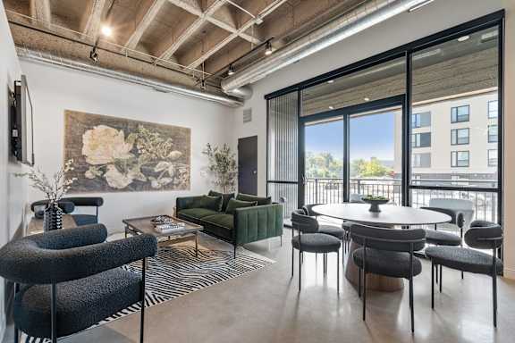 A living room with a large painting on the wall and a view of a balcony.