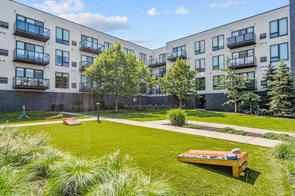 A grassy area with a bench in front of apartment buildings.