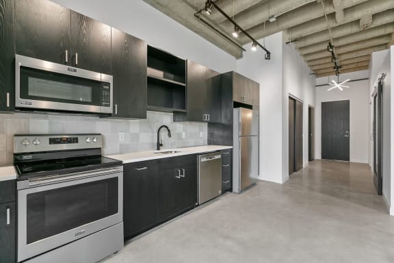 a kitchen with black cabinets and stainless steel appliances