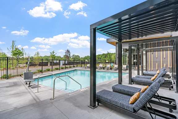 A pool with sun loungers and a building in the background.