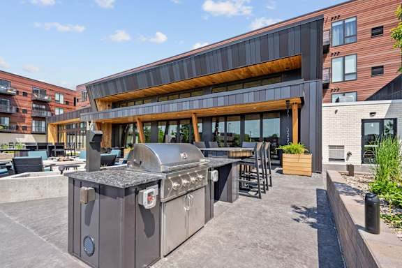 A large outdoor BBQ grill is in the middle of a patio.