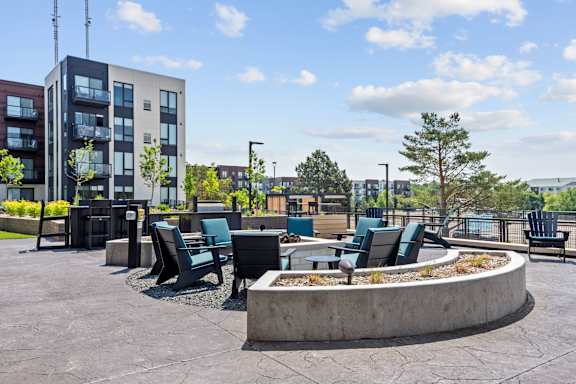 A modern outdoor seating area with a circular fire pit in the center.