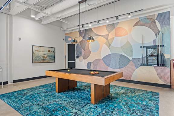 A pool table in a room with a colorful mural on the wall.