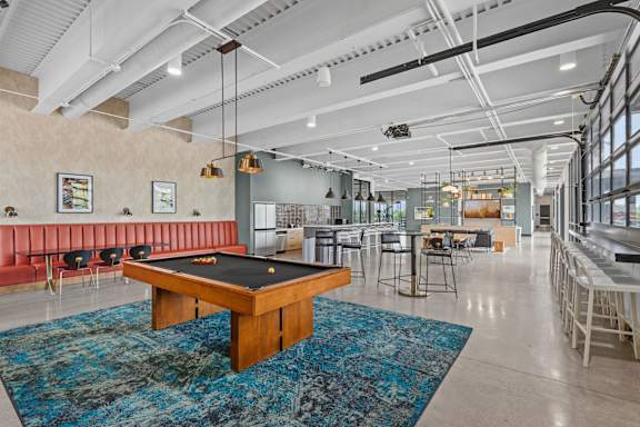 A room with a pool table and a bar area.