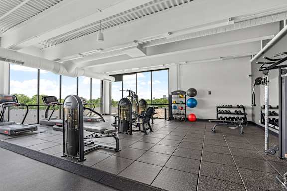 A gym with treadmills, exercise balls, and weight racks.