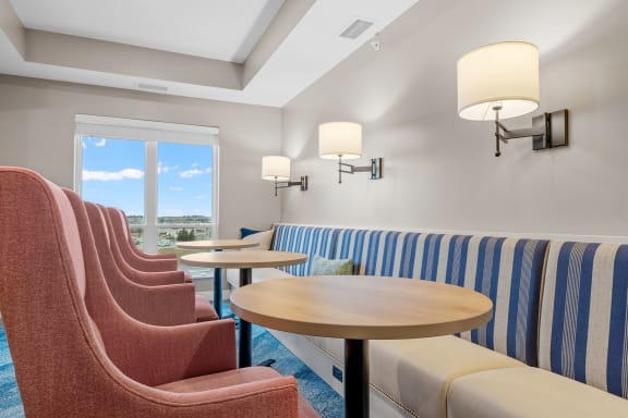 a lounge area with chairs and tables and a window