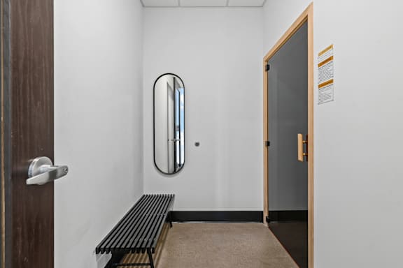 A hallway with a bench and a mirror on the wall.