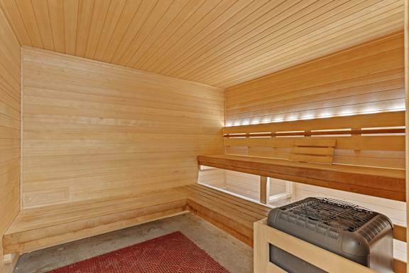A wooden sauna with a bench and a mat on the floor.