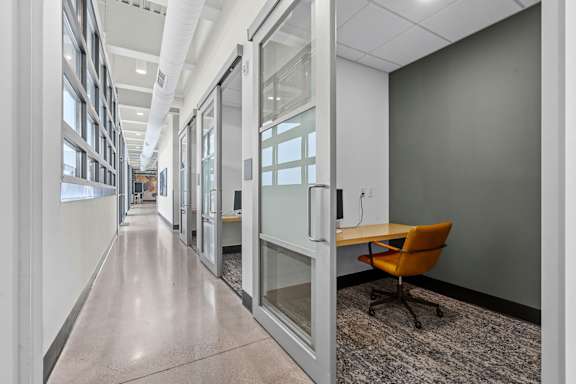 A long hallway with glass walls and a yellow chair.