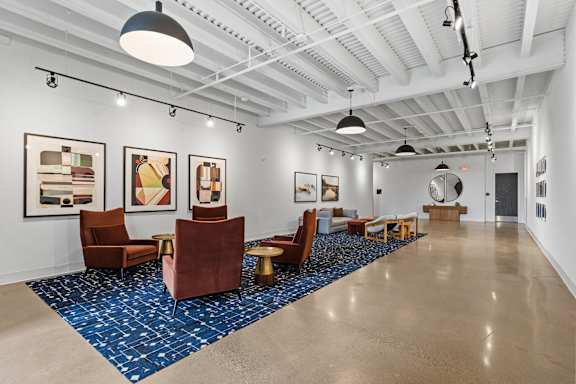A spacious room with a blue carpet and brown chairs.