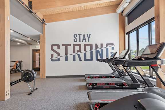 A gym with treadmills and a wall that says "Stay Strong".