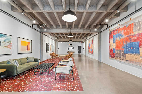 A large room with a long table and chairs and a large painting on the wall.