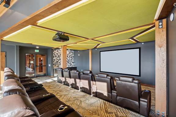 A home theater with a row of brown leather chairs and a large screen.