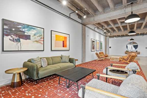 A living room with a green couch and a painting on the wall.