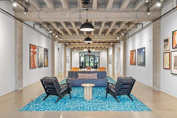 A room with a blue rug and chairs.