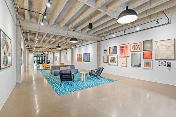 A spacious art gallery with a blue carpet and artwork on the walls.