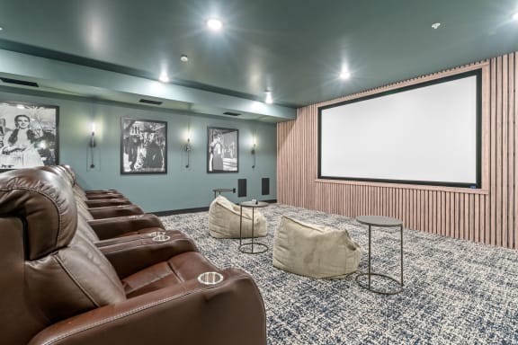 a theater room with leather couches and a projector screen